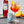 Load image into Gallery viewer, Lifestyle image of a can of Folkington&#39;s 150ml Soda Water with a bottle of Campari open in the background. Next to the can is a glass of Campari and Soda Water with ice and a slice of Orange to garnish.
