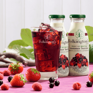 Lifestyle shot of a glass of summer berries with ice, and 2 bottles of summer berries in the background