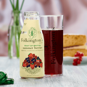 Bottle of Summer Berries, a glass of drink and a piece of Victoria sponge cake - with  flowers behind.