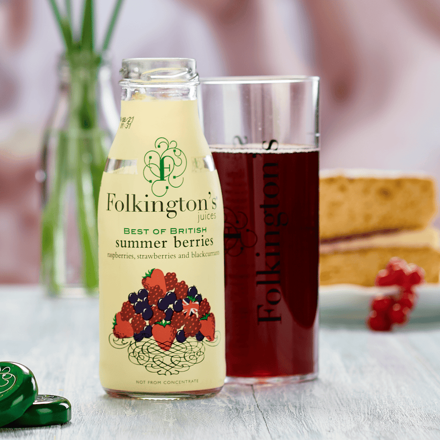 Bottle of Summer Berries, a glass of drink and a piece of Victoria sponge cake - with  flowers behind.